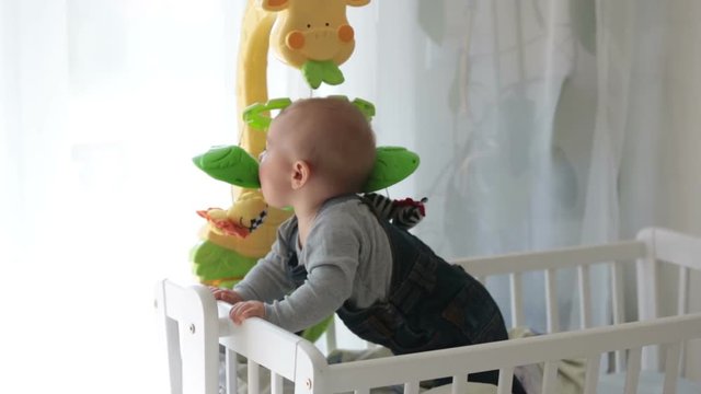 Sad baby boy, crying in crib at home