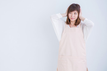 耳をおさえるエプロン姿の女性
