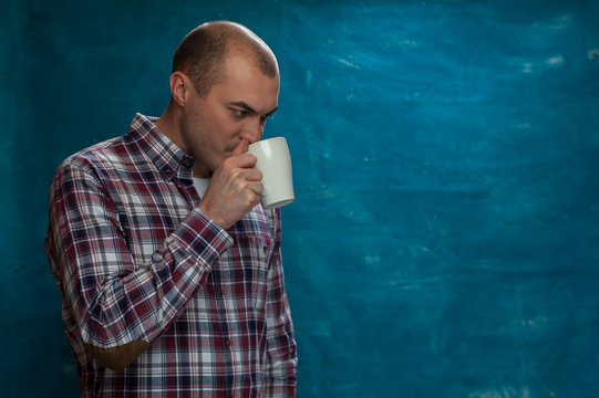 Confident young man wearing casual cloth posing with coffee mug in hands