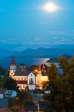 Moon rising between the clouds over Puerto Varas at the shores of Lake Llanquihue with Osorno Volcano in the back, X Region de Los Lagos, Chile