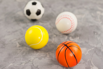 Scattered four new soft rubber basketball and baseball and tennis and soccer balls on old worn cement