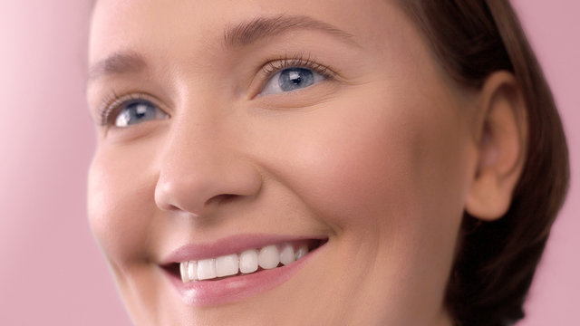 closeup portrait of middle age woman showing her skin closeup with ideal skin smiling on pink