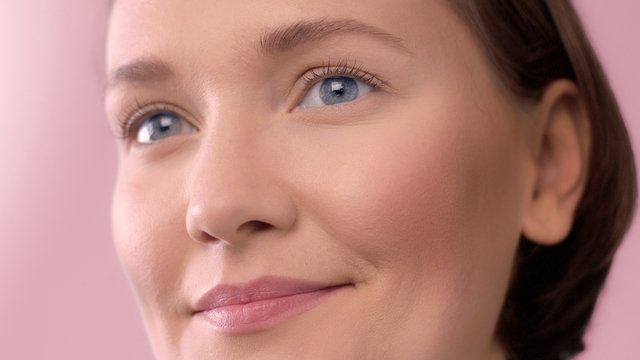 closeup portrait of middle age woman showing her skin closeup with ideal skin smiling on pink