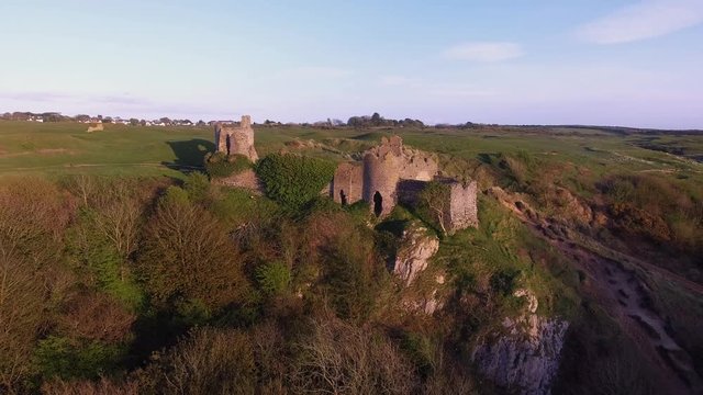 The ruins of Pennard castle on the Gower peninsula in Swansea, South Wales, UK, overlooking Three Cliffs Bay with Pennard Golf Club in the background.