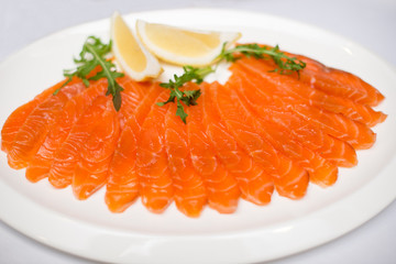 red sliced fish on plate withlemon on white background.