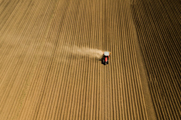 Farmer with a tractor on the agricultural field sowing. tractor working on the agricultural field in spring. aerial view by drone