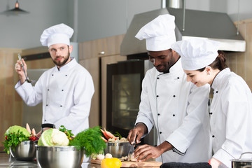 Multiracial chefs team sharing experience while cooking on modern kitchen