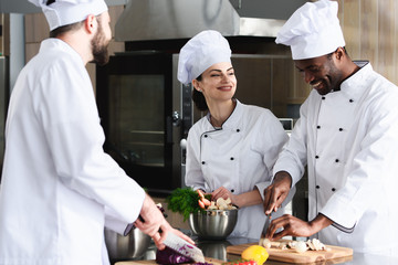 Multiracial team of cooks working together in restaurant kitchen