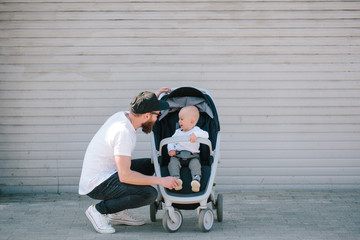 Father walking with a stroller and a baby in the city streets