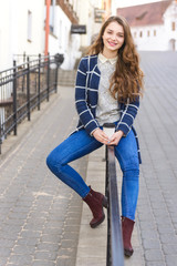 Cheerful  stylish  young woman in street drinking coffee