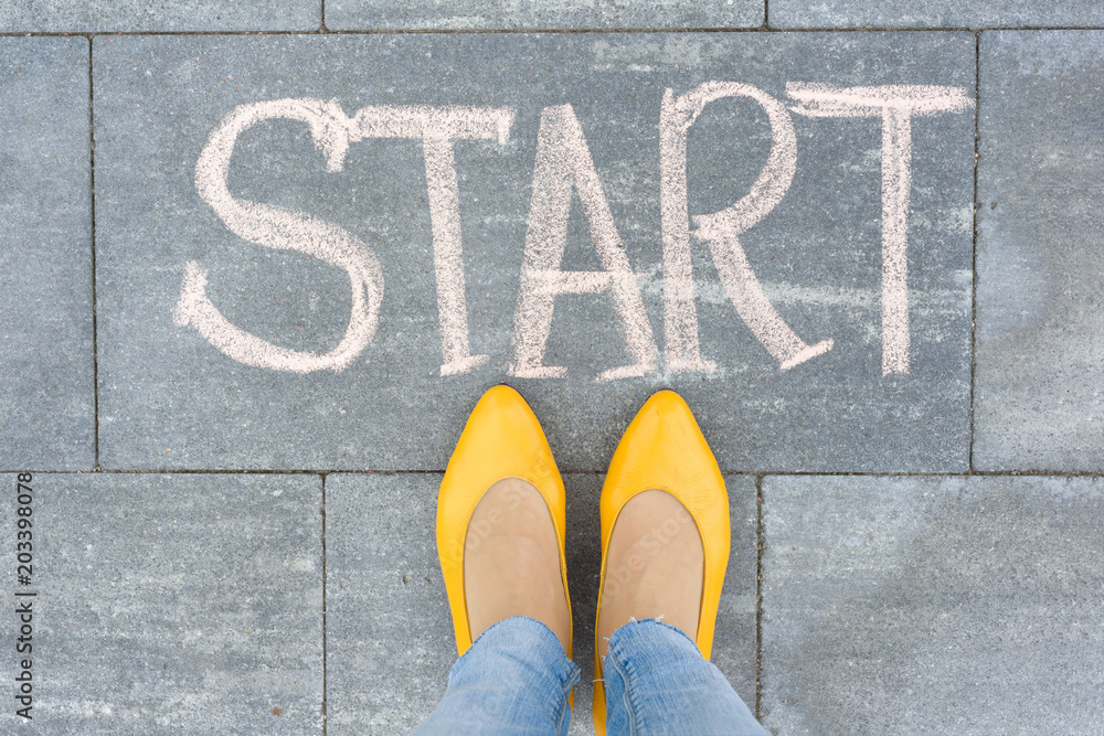 Wall mural word start on the asphalt and feet woman