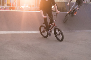 Young people riding a Bmx bike in a skate park in the background of the sunset. Bmx Concept. Bmx Bicycle Training