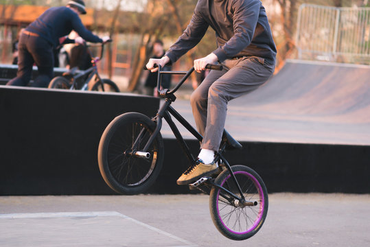 Bmx rider makes tricks on BMX in a skateboard. Evening training at Bmx. A cyclist travels on the rear wheel. Bmx Concept