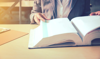 Business woman reading book and use tablet to search her research in library