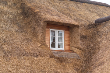 Fototapeta na wymiar Fenster in einer Gaube mit Reetdach