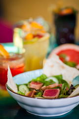 Salads from fresh products with meat, fish, chicken and vegetables on the table among colorful refreshing cocktails with ice.