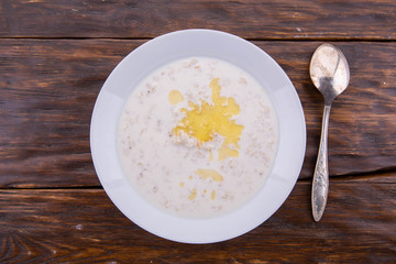 Porridge with butter on a dark wooden background with a spoon
