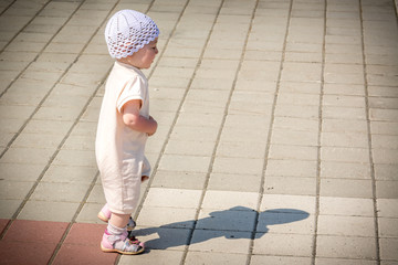 A small child in a white suit running around the paved path from the quay of the river port
