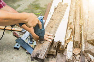 Construction by woodwork. Carpenter working of wood drilling hole and old wooden in his hands.