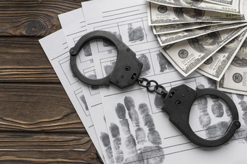 handcuffs, fingerprint map with fingerprints. American dollars on a wooden background. arrest, deposit.