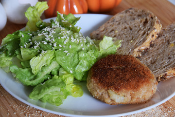 fried minced chop with bread and lettuce sprinkled with sesame seeds