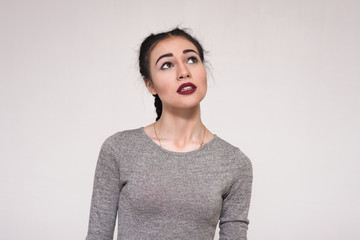 Portrait of a beautiful brunette girl on a gray background showing her emotions