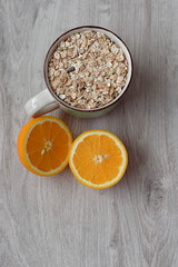 Still life healthy breakfast of muesli and oranges on a wooden background. Top view.