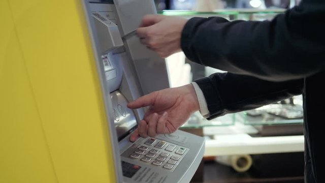 Man using his credit card in an atm for cash withdrawal, pin code money shopping mall