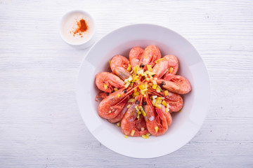 Shrimps in a white plate on a white wooden background