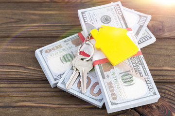 keychain with keys from the house on packs of American dollars on the background of a wooden table. mortgage, mortgage, sales of immovability