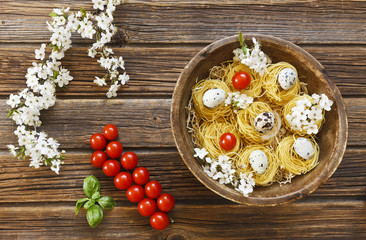 Obraz na płótnie Canvas Close-up of raw traditional Italian pasta with cherry tomatoes, quail eggs and basil. Top view on vintage wooden background