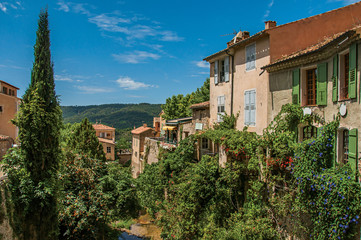 Fototapeta na wymiar View of houses near creek and bluff with vegetation in the charming village of Moustiers-Sainte-Marie. In the Alpes-de-Haute-Provence department, Provence region, southeastern France