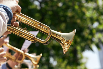 Closeup of European musicians playing on a golden trumpet.