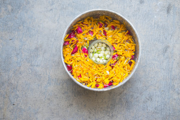 Water in bowl mixed with perfume and flowers