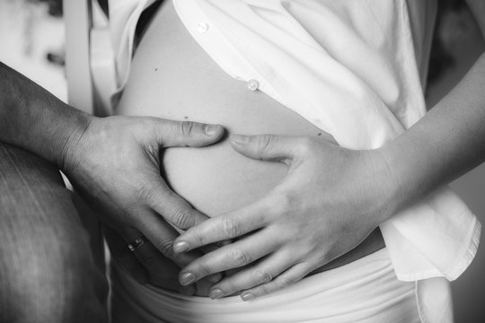 Pregnant belly.Wife and husband.Close-up view.Black and white.