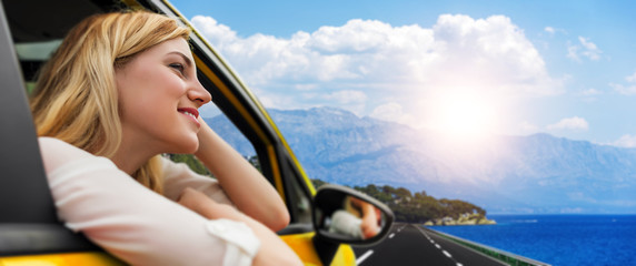 Travel or vacation. Beautiful blond girl in car on the road to the sea.