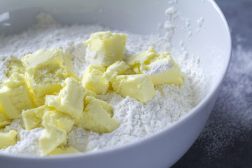 Large white mixing bowl with wheat flour and butter mixture prepared for baking in the kitchen