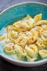 Closeup of italian tortellini served in bouillon, vertical shot, selective focus