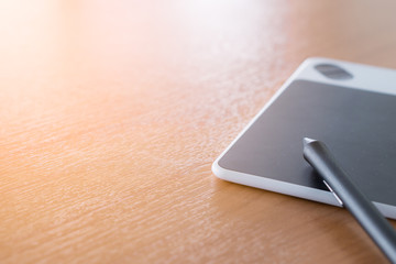 the stylus pen and the pad are on the wooden desk.