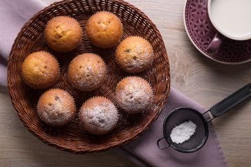  Muffins in a wicker plate with a cup of milk. Top view.