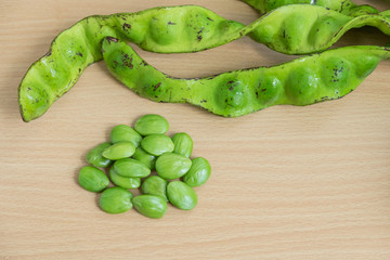 Green Tropical stinking edible beans and sheath shell on wood background (Parkia Speciosa) with copy space