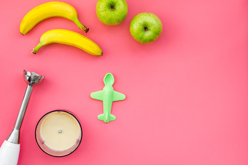 Homemade baby food. Cook puree with apple and banana with immersion blender. Pink background with...