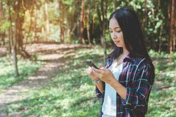 traveler woman using touching on mobile phone ready start to walking on forest way go to hiking travel camping. holiday adventure trekking travel concept.