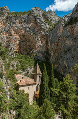 Fototapeta na wymiar View of the church Notre-Dame de Beauvoir amid the cliffs, above the charming village of Moustiers-Sainte-Marie. In the Alpes-de-Haute-Provence department, Provence region, southeastern France