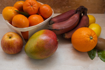 Fresh healthy tropical fruits. Summer food, vitamins concept.Basket of ripe mandarins,apple,mango,red bananas,lemons,orange and kiwi.