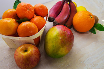 Fresh healthy tropical fruits. Summer food, vitamins concept.Basket of ripe mandarins,apple,mango,red bananas,lemons,orange and kiwi.