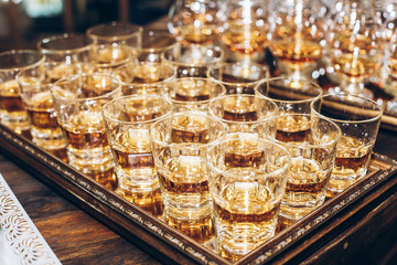 stylish glasses with cognac or whiskey on table at wedding reception. alcohol bar. tasty drinks for celebrations and events. luxury stylish catering. christmas and new year feast