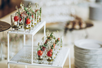 delicious appetizers starters with tomatoes and cheese in glass on plate on table at wedding reception. luxury catering at celebrations