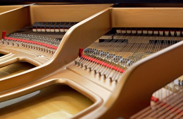 Inside a piano playing, dampers, felt hammers, action, metal strings and metal frame, red and white...