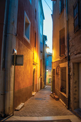 Fototapeta na wymiar View of narrow alley in the early evening with lamp lit, in the lovely village of Rians. Located in Var department, Provence region, in southeastern France.